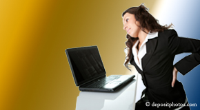 a person Concord, NC bending over a computer holding her back due to pain